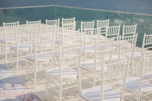 White chairs closeup on background of wedding arches peach color with flowers on the background of the sea.